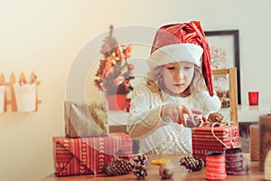 Child girl preparing gifts for christmas at home, cozy holiday interior