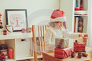 Child girl preparing gifts for christmas at home, cozy holiday interior