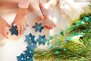 Child girl preparing  winter holidays at home. She sitting on floor and playing with Christmas toys