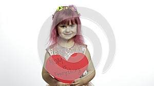 Child girl princess holds red paper heart with text about mother. Mother`s day