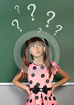 Child girl with question mark on school blackboard
