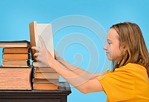 Child girl reading a book, operating on a stack of books