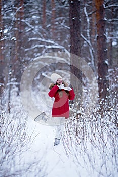 Child girl in a red jacket on the snow in a winter park. Frost and snowy winter, recreation for children and walks, mood and snow-