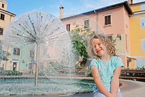 Child girl relaxing at fountain in Izola (Isola) city in Slovenia.