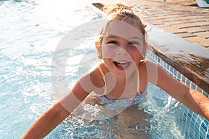 Child girl relaxing at the pool on a sunny hot summer day. Poolside resort concept, heat wave, climate change