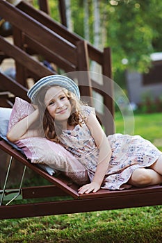 Child girl relaxing on sunbed in sunny garden