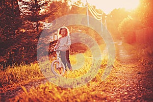 Child girl riding bicycle on summer country road