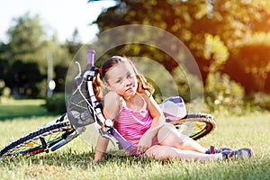 Child girl riding bicycle on summer sunset in the park.