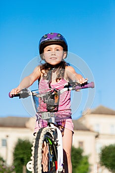 Child girl riding bicycle on summer sunset in the park.