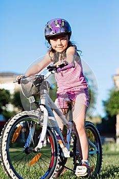 Child girl riding bicycle on summer sunset in the park.