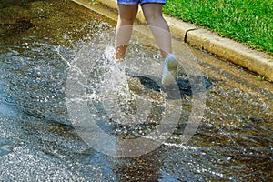 child girl running and jumping in puddles after rain in summer
