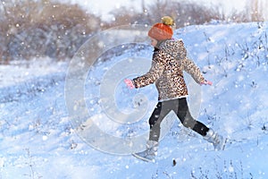 Child girl runs and having fun in the winter forest, bright sunlight and shadows on the snow, beautiful nature