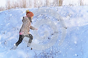 Child girl runs and having fun in the winter forest, bright sunlight and shadows on the snow, beautiful nature