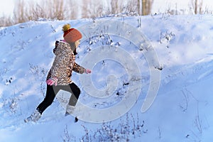 child girl runs and having fun in the winter forest  bright sunlight and shadows on the snow  beautiful nature