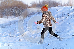 Child girl runs and having fun in the winter forest, bright sunlight and shadows on the snow, beautiful nature