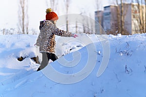 Child girl runs and having fun in the winter forest near city, bright sunlight and shadows on the snow, beautiful nature