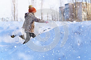Child girl runs and having fun in the winter forest near city, bright sunlight and shadows on the snow, beautiful nature