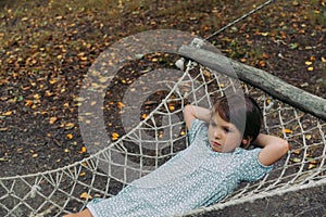 A child girl is sad in a hammock. Autumn has come
