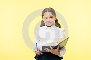 Child girl school uniform clothes hold book and pen. Girl cute write down idea notes. Notes to remember. Write essay or