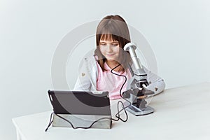 Child girl in science class using digital microscope. Technologies, children and learning concept.