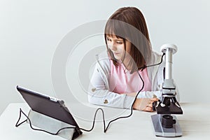 Child girl in science class using digital microscope. Technologies, children and learning concept.