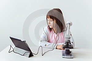 Child girl in science class using digital microscope. Technologies, children and learning concept.