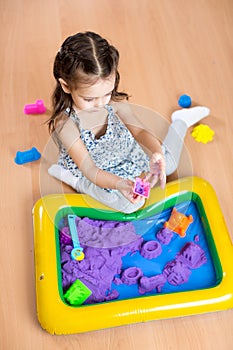 Child girl sculpts from kinetic sand in play room. Preschool. photo