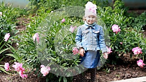 Child girl send air kisses. Garden with peonies and funny baby