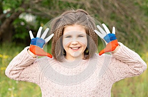 Child girl show hands painted in Russia flag colors walking outdoor. Day of Russian flag. Patriots citizens nationality