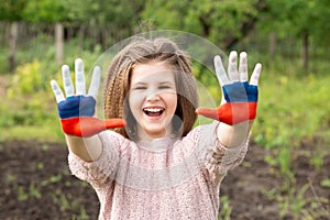 Child girl show hands painted in Russia flag colors walking outdoor. Day of Russian flag. Patriots citizens nationality