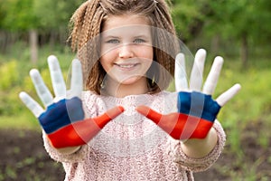 Child girl show hands painted in Russia flag colors walking outdoor. Day of Russian flag. Patriots citizens nationality