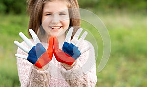 Child girl show hands painted in Russia flag colors walking outdoor, focus on hands. Day of Russian flag. Patriots