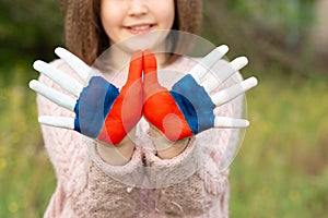 Child girl show hands painted in Russia flag colors walking outdoor, focus on hands. Day of Russian flag. Patriots