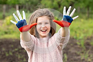 Child girl show hands painted in Russia flag colors walking outdoor, focus on hands. Day of Russian flag. Patriots