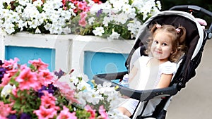 Child girl sits in a baby carriage and smiles.