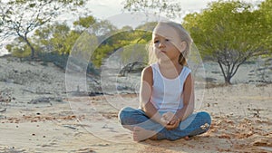 Child girl sits at desert and pondering somethink with thousand-yard stare