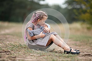 Child girl sits on grass with her newborn brother on walk in par