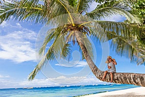 Child girl sitting on palm tree, tropical beach vacation