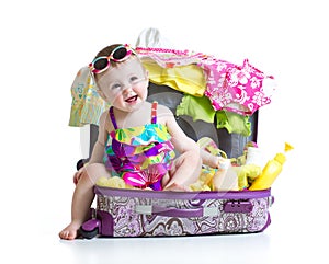 Child girl sitting in suitcase with things for