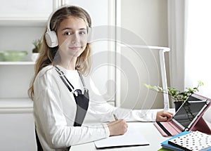 Child girl sitting at table and studing.Online education. Zoom school.Student kid.Home learning photo
