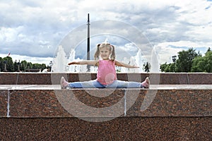 Child girl sitting on a twine at the edge of the fountain