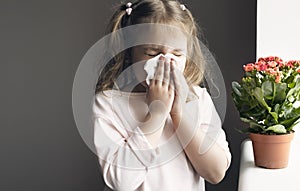 Child girl sneezing,caucasian kid blowing napkin,allergic concept. Flower allergy