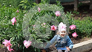 Child girl sniffs the aroma of peony flower and sneezes. Children`s allergies.