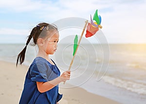 Child girl with a spinning pinwheel on the beach