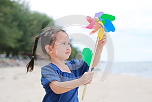 Child girl with a spinning pinwheel on the beach