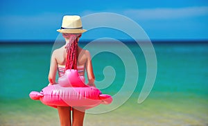 Child girl stands with her back with a Flamingo lifeline on beach