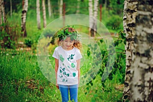Child girl in summer forest. Idea for nature crafts with kids - leaf print shirt and natural wreath.