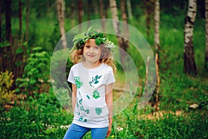 Child girl in summer forest. Idea for nature crafts with kids - leaf print shirt and natural wreath