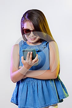 child girl in sunglasses using smartphone on white background