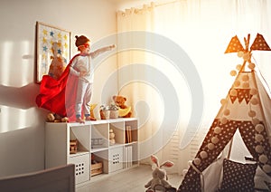 Child girl in a super hero costume with mask and red cloak